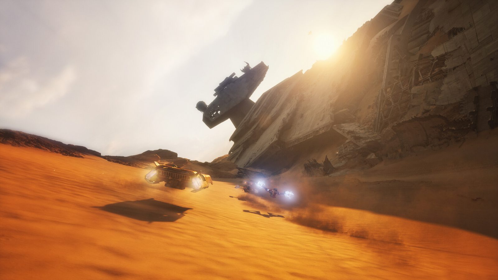 Two podracer-style vehicles race across an orange desert past a crashed Star Destroyer