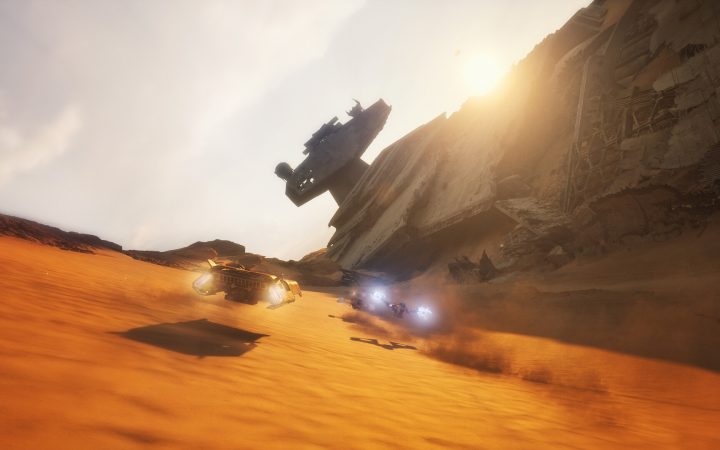Two podracer-style vehicles race across an orange desert past a crashed Star Destroyer